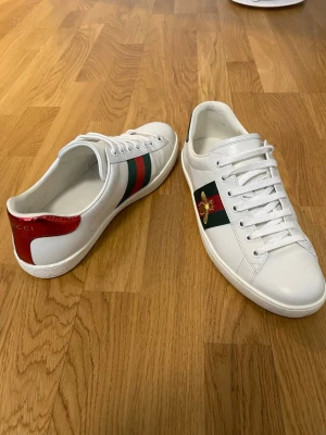 Gucci Ace - Säljer ett par vita Gucci Ace skor som har använts några fåtal gånger men är i mycket bra skick utan några defekter. Det är storlek 43 men passar även storlek 44. Ny pris: 7736kr. Skriv vid minsta fundering 😊✨Kvitto finns även! Obs! Pris kan alltid diskuteras.