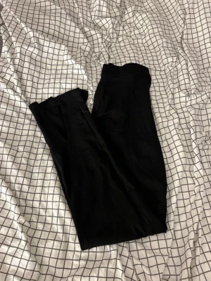 Svarta vida byxor från NA-KD XS - Säljer ett par svarta kostym liknade byxor från NA-KD i storlek XS. Byxorna har hög midja och ett rakt, lite vidare ben som ger en chill och trendig look, slits nertill. Tillverkade i mjukt material som känns skönt mot huden. Perfekta till sneakers eller boots.