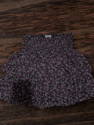 Blommig kortkjol från Kappahl - Vi kan diskutera priset. Supersöt kortkjol från Kappahl med småblommigt mönster i lila, rosa och vitt. Kjolen har smock i midjan och volangkant som ger en luftig och lekfull känsla. Perfekt för dig som gillar romantisk stil och vill ha något bekvämt och trendigt. Storlek 158-164 