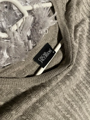 Beige stickad tröja Oscar Jacobson - Säljer en beige stickad tröja från Oscar Jacobson i storlek M. Tröjan har ett klassiskt kabelstickat mönster, rund halsringning och långa ärmar. Perfekt nu mot våren. Superenkel att matcha till olika outfits.