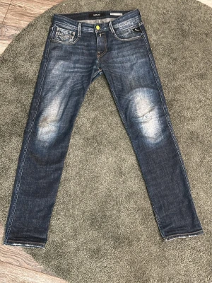 Replay Anbass Slim Fit Jeans Blå 30 - Säljer ett par Replay Anbass slim fit jeans i klassisk blå tvätt med slitningar på knäna och snygga detaljer på bakfickorna. En defekt är att de är påväg att spricka i skrevet men är en enkel fix för den som orkar. Annars väldigt bra skick