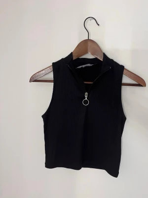 Svart ribbad croppad linnetopp - Säljer en svart croppad linnetopp med ribbad struktur och dragkedja framtill med rund metallring. Säljer då jag rensar ut min garderob ❣️