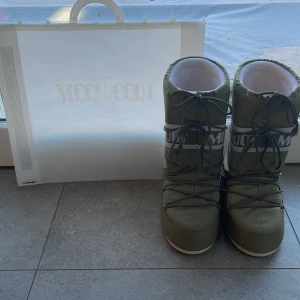 Khakigröna Moon Boots Icon Nylon - Moon Boot Icon Nylon – Khaki (Herr) Säljer ett par klassiska Moon Boot Icon Nylon i färgen khaki för herr. Skorna är endast knappt använda och därför i mycket fint skick. Inköpta från Miinto. Nypris: 1 850 kr. Ingår dustbag. Ett utmärkt val för dig som söker både funktion och stil under vintern.