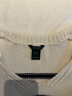 Randig stickad tröja från Lindex XS - Krämvit stickad tröja från Lindex i storlek XS. Tröjan har svarta ränder, v-ringad hals och ribbade muddar vid ärmslut och nederkant. Perfekt för dig som gillar en enkel men snygg look.