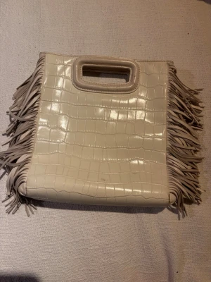 Majeväska - Säljer en vit/beige majeväska. Pris går att diskutera Väskan har ett inbyggt handtag och avtagbar axelrem, vilket gör den enkel att bära på olika sätt. Perfekt för dig som gillar stockholmstilen!