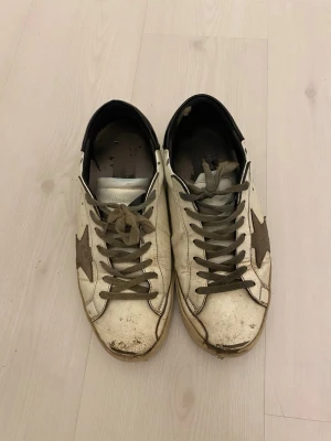 Golden goose skor - Säljer ett par golden goose skor 2 hål i båda bakre sulorna sedan finns det lite slitage på sulorna men de går att fixa lätt med superlim. ”Skorna är väldigt smutsiga på bilden och blöta”.