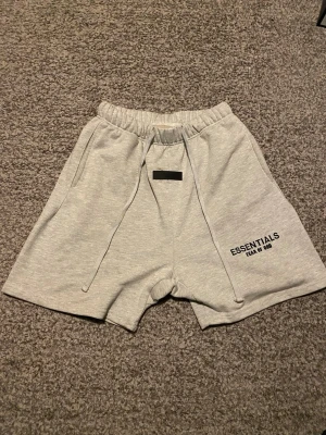 Essentials shorts ljusgrå - Ett par ljusgråa essentials short som jag har använt få gånger. Bry er inte att de är lite smutsig på bilden jag tvättar innan ni köper. Skriv om ni är intresserade!!