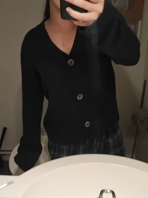 Marinblå kofta med knappar - Mysig svart kofta med stora knappar med en v-ringad hals. Den är lite loose och den är använd ett fåtal gånger.