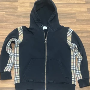 Burberry zip hoodie  - Säljer en stilren Burberry zip hoodie i svart färg. Använd endast några få gånger och är i mycket bra skick. Hoodien är mjuk, skön och av hög kvalitet med en tidlös design. Passar både storlek XS och S. Passar perfekt för alla dagar 