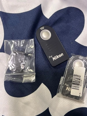 Fjärrkontroll och filterkit för Nikon systemkamera - Paket med fjärrkontroll för Nikon systemkameror, objektivlock samt filterkit i praktiskt fodral. Fjärrkontrollen och locken är nya i förpackning, filtret i bra skick. Perfekt tillbehör för fotografer som vill ha extra kontroll och skydd till sin kamera.