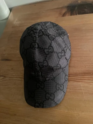 Svart Gucci keps med GG-mönster - Säljer äkta Gucci keps som är lite använt och vill gärna sälja den snabbt plus att jag behöver pengar säljer jag den billigt