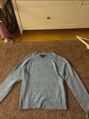 Ljusblå stickad tröja från Vero Moda - Mysig ljusblå stickad tröja från Vero Moda med rund halsringning och ribbade muddar vid ärmslut och nederkant. 