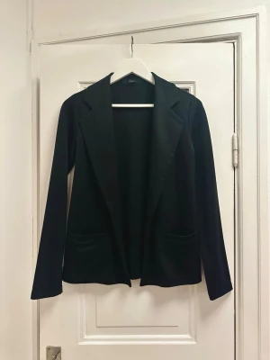 Svart kavaj i mjukt material - Svart kavaj/blazer i mjukt stretchigt material. Slappare mer vardaglig kavaj pga dess mjuka tyg. Köpt hos Forever 21.