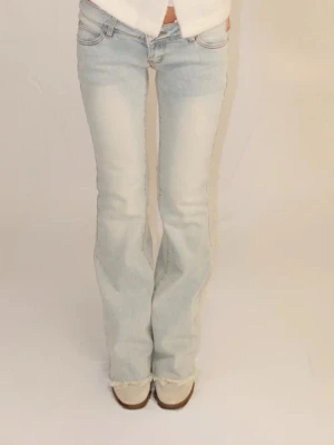 Ljusblå bootcut jeans med slitningar - Säljer ett par ljusblå jeans med bootcut-modell och snygga slitningar på benen. Jeansen är tillverkade i ett mjukt denimtyg. 