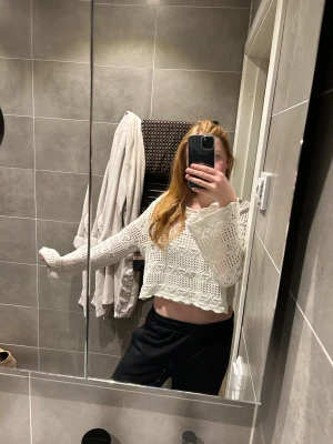 Vit stickad croppad tröja från Monki - Säljer en vit stickad tröja från Monki i storlek L. Tröjan är croppad med lång ärm och har ett snyggt virkat mönster och vågig kant nertill. Perfekt för vår och sommar när du vill ha en chill och luftig look.