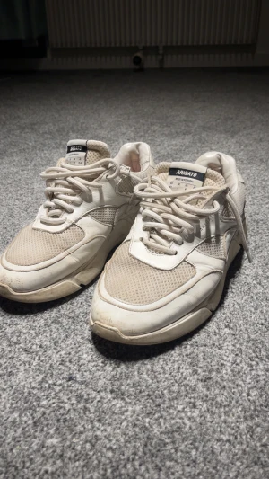 Vit-beige sneakers från Axel Arigato - Säljer ett par chunky sneakers från Axel Arigato i vit och beige färg. Skorna har meshpaneler och detaljer i skinn, samt snörning och platt sula. Märket syns på tungan och sidan. Perfekt för dig som gillar stilrena och sportiga sneakers. Nypris 2800.