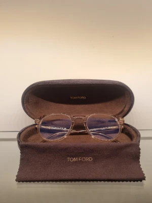  Tom Ford glasögon  - Snygga transparenta glasögon från Tom Ford med en  stilren design. Bågarna är i ljus plast med diskreta gulddetaljer vid gångjärnen. Kommer med originalbrunt fodral och putsduk med Tom Ford-logga. Glasögon är I styrka 1 alltså inte så mycket alls och passar alla. Priset är inte spikat I en sten så hör gärna av er vid funderingar. :)