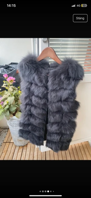 Mörkgrå fluffig pälsväst - Säljer en riktigt snygg och fluffig svart pälsväst med breda horisontella paneler. Västen har en lyxig look med extra volym vid axlarna och är perfekt för att ge din outfit en trendig touch.