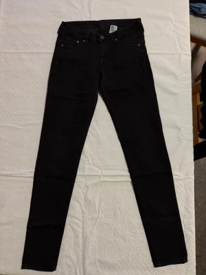 Svarta super skinny jeans H&M - Svarta super skinny jeans från H&M med låg midja. Klassisk femficksmodell med smala ben och stretchigt jeanstyg som sitter tight hela vägen ner. Perfekta för dig som gillar en slimmad look och vill ha ett par riktigt svarta jeans.