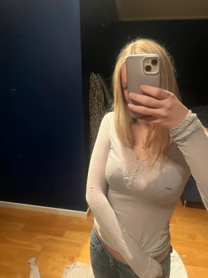 Ljusgrå intimissimi - Säljer en ljusgrå långärmad topp med snygg v-ringning och spetsdetaljer vid halsen och ärmsluten. Tunn och mjuk i materialet.