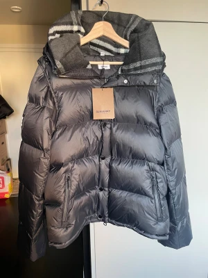 Burberry pufferjacka - Jacka fån Burberry i storlek XL med avtagbara ärmar så den kan användas som väst. Jag fick den i present men är oanvänd eftersom den passade inte mig. Bästa priset ni kommer hitta för en helt ny! Ni är välkomna att skicka prisförslag!