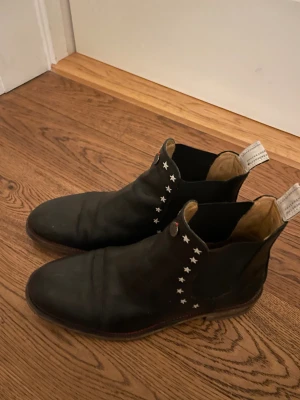 Odd Molly Svarta chelsea boots med stjärndetaljer - Snygga svarta chelsea boots i skinn med coola silverfärgade stjärnor längs sidan. Rund tå och platt sula, med dragflikar bak för enkel påtagning. Perfekt för dig som vill ha boots med lite edge och unik detalj.