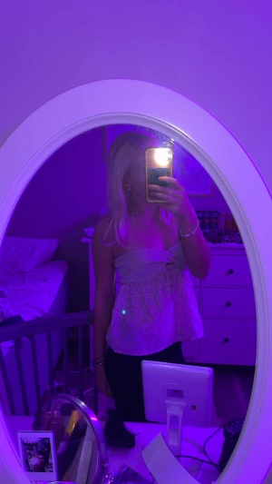 Vit tubtopp med broderade blommor - Säljer en söt vit tubtopp med broderade blommor och hålmönster. Toppen har bandeau-modell med twistad detalj framtill och är helt axelbandslös. Perfekt för sommarens varma dagar och ger en fräsch och feminin vibe.