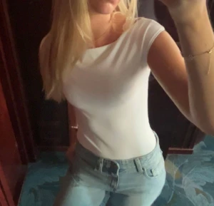 Vit body - Minimalistisk vit body med bred båturringning och ärmlös design. Perfekt att styla med jeans eller kjol för en clean look. Gjord i mjukt material som sitter tight mot kroppen.