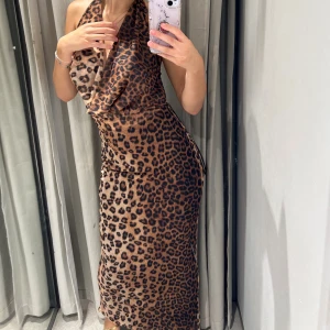 Leopardmönstrad långklänning med öppen rygg - Säljer en snygg långklänning med leopardmönster och halterneck. Klänningen har en figurnära passform och öppen rygg med tunna band. Perfekt för dig som vill sticka ut och älskar djurmönster. Materialet känns mjukt och följsamt.