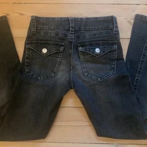 Svarta bootcut jeans med låg midja - Säljer ett par svarta jeans från Gina Tricot med låg midja och bootcut-ben. Jeansen har knappar på bakfickorna. Använda men inget som syns, inga skador/ defekter.💕 Säljer då de tyvärr har blivit för små🤍