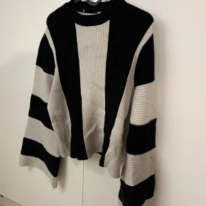 Randig svart och grå/vit ribbad tröja - Tröja med breda svarta och grå ränder. Tröjan har en loose passform, vida ärmar och ribbad struktur. 