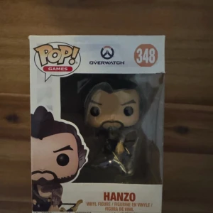 Funko Pop! Games Overwatch Hanzo #348 - Säljer en Funko Pop! Games Overwatch Hanzo #348 vinylfigur. Figuren är helt ny och oöppnad i originalförpackning, perfekt för samlare eller fans av Overwatch. Kartongen är i mycket fint skick utan synliga skador eller slitage.