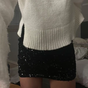 Svart paljettkjol, glitter kjol  - Supersnygg svart kortkjol från H&M täckt med glittriga paljetter. Kjolen har en tight passform och är perfekt för festligare tillfällen. Materialet är mjukt och stretchigt syntet, vilket gör den bekväm att bära hela kvällen. Använd en gång. 