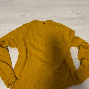 Gul stickad tröja  - Mysig gul stickad tröja med rund halsringning och långa ärmar. Perfekt för lager på lager under kyliga dagar.