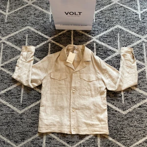 Beige linneskjorta från These Glory Days - Snygg beige skjorta i linne från These Glory Days, storlek medium. Skjortan har klassisk krage, två bröstfickor med lock och knappar framtill. Perfekt för dig som gillar stilrena och luftiga plagg med en chill vibe.   Hör gärna av dig vid frågor!