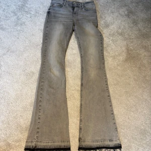 Grå bootcut jeans från Gina tricot - Snygga grå jeans från Perfect Jeans med bootcut-modell och råa kanter nedtill. På nedre bakbenet är det ett litet märke och själva  dragkedjan har gått av men man får ändå upp gylfen utan problem!