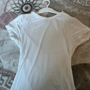 Tight vit tshirt från ginatricot - Enkel vit t-shirt med rund hals och korta ärmar. Perfekt till jeans eller shorts och superlätt att matcha med andra plagg. Gjord i mjuk bomull för en skön känsla hela dagen.