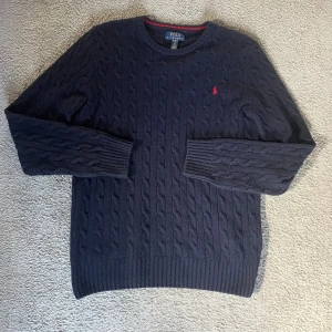 Ralph Lauren tröja - Säljer en Ralph Lauren kabelstickad tröja. Den är sparsamt använd och har inga defekter. Nypris:1995.                                                                         Hör av dig vid minsta fundering