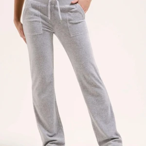 Grå mjukisbyxor med snörning - Superbekväma grå mjukisbyxor med raka ben, snörning i midjan och stora fickor fram. Byxorna har även bakfickor med knappdetalj och är perfekta för en chill och avslappnad stil. Tillverkade i mjukt material som känns skönt mot huden.