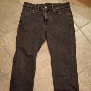 Svarta regular fit jeans från H&M - Svarta jeans från H&M i regular fit med klassisk femficksdesign och raka ben. Jeansen har en enkel look med svarta sömmar och knappstängning. Perfekta för dig som gillar en stilren och avslappnad vibe.