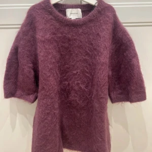 Vinröd stickad tröja från H&M Edition - Supermjuk och fluffig lila stickad tröja från H&M Edition. Tröjan har en avslappnad passform, rund halsringning och halvlånga ärmar. Perfekt för lager-på-lager och ger en mysig vibe till din outfit.
