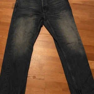 Weekday blå straight jeans 30/32 - Blå jeans från Weekday i modellen Space Relaxed Straight Jeans. De har en rak passform och klassisk femficksdesign. Jeansen är tillverkade i 100% bomull och har en avslappnad vibe med lite tvättade detaljer. Perfekta för dig som gillar en enkel och stilren look. Aldrig använda. Stl 30/32