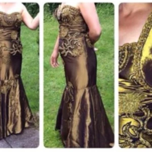 Guldig och brun/grön långklänning med brodyr - Säljer en elegant långklänning i guld och brunt/grönt med vackra broderade detaljer och figurnära passform. Klänningen har axelbandslös design och markerad midja, perfekt för dig som vill sticka ut med en lyxig look.