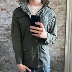 Field Jacket - Riley - Mycket fint skick, inga defekter. Storlek 48/S passar dig som är mellan 178-185cm ungefär. Nypris ca 2000kr. Modellen är 185 cm, 79 kg. Passar bra nu till vintern. Skriv för mer information!🤝