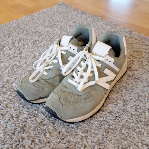 New Balance 574 skor - Säljer dessa New Balance 574 skor i storlek 44. Riktigt fräscha och snygga är dem med mocka på utsidan. Skorna har använts fåtal gånger och skicket är jättebra, inga slitningar och skador eller så. Skick: 8/10