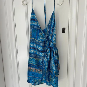 Blå omlottklänning från Zara - Supersnygg blå omlottklänning från Zara! Aldrig använd då den var för liten, prislappen är kvar! Perfekt för en varm resa💕