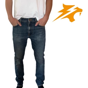 Blå jeans från Nudie Jeans, 29/30 - Snygga blå jeans från Nudie Jeans i klassisk femficksmodell. Jeansen har raka ben, orangea sömmar och subtila slitningar för en cool look. Tillverkade i slitstarkt bomullsjeans med normal passform och medelblå tvätt.