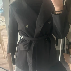 Svart trenchcoat från H&M  - Stilren svart trenchcoat från H&M. Perfekt till hösten. Bara använt 1 gång och är i väldigt fint skick!