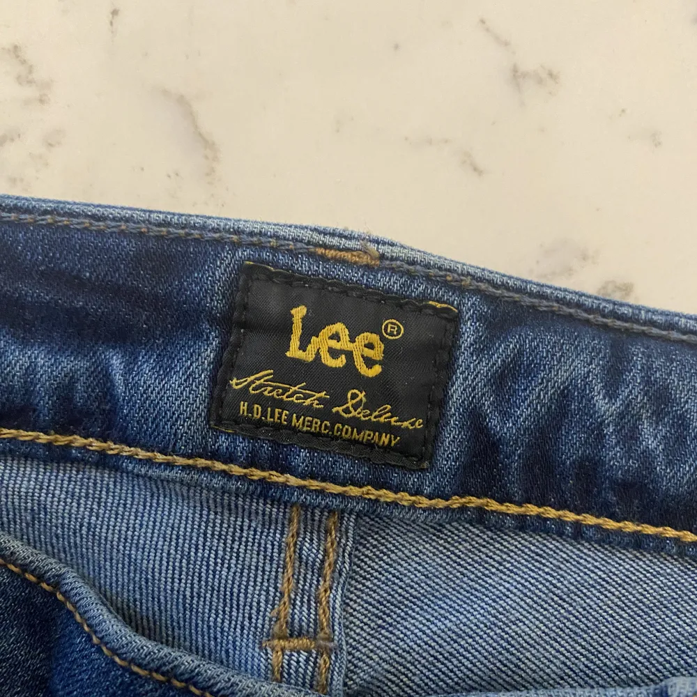 Lågmidjade Lee jeans med bootcut, hål på ena benet. Storlek W28 L33 passar S. Jeans & Byxor.