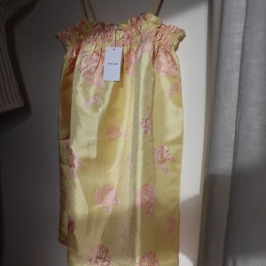Gul klänning med rosa blommor - Gul klänning med rosa blommor. Köpt i Danmark, helt oanvänd, perfekt skick! Prislappen är fortfarande på, köpte för att ha på ett bröllop men blev en annan klänning så därför säljer jag den 💐